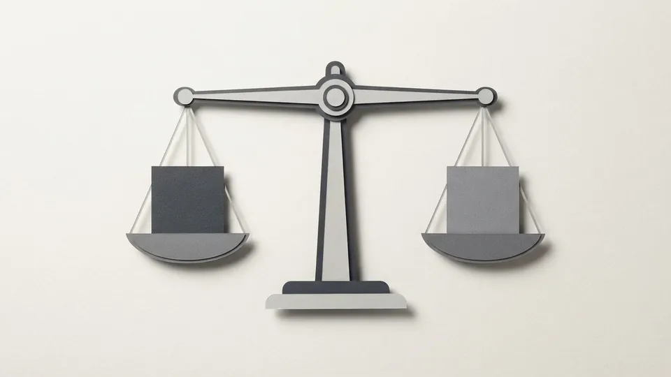A cut-paper balance scale holding a grey paper tile in each pan, the beam perfectly level