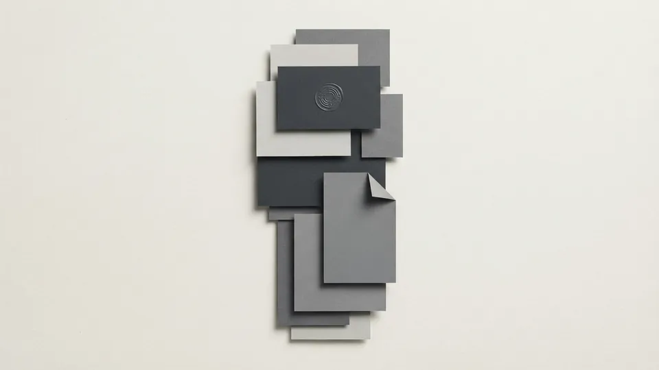 A vertical feed of overlapping grey paper cards, one marked with a small embossed seal and one with a folded corner