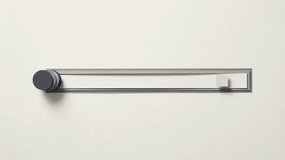A long thin paper track with a heavy stack of graphite discs at one end and a single light grey tile far along it